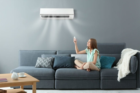 Homeowner sitting on the couch underneath their ductless mini-split air conditioner