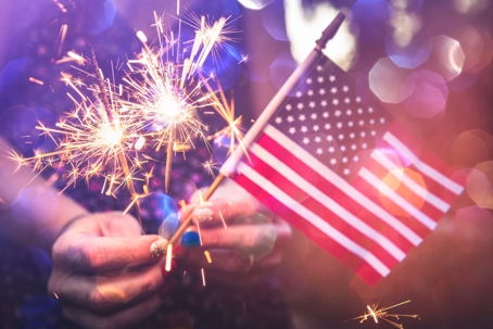Person holding sparklers and the American flag