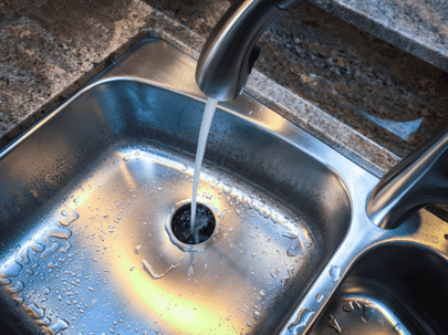 Water running into a garbage disposal in a newly renovated kitchen
