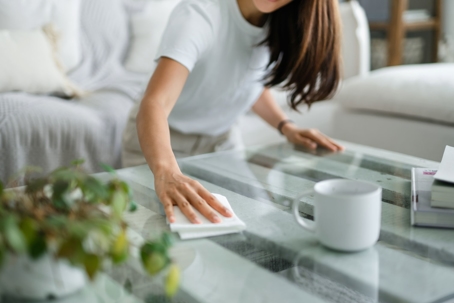 A homeowner wiping down their living room coffee table with a paper towel