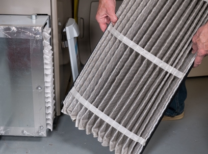 man changing pleated air filter in a furnace