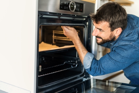 man inspecting oven