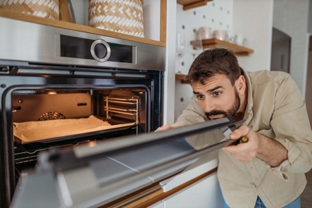 man inspecting oven