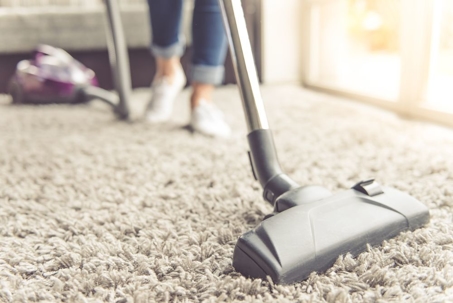 Person vacuuming carpet in modern home