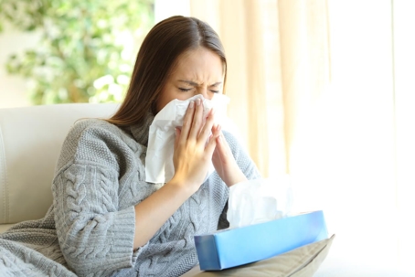 woman sneezing into tissue