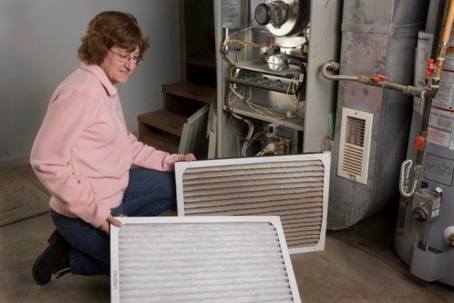 woman changing  a dirty furnace filter