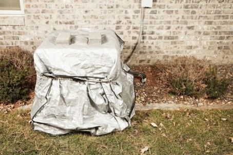 outdoor air conditioner covered by a tarp
