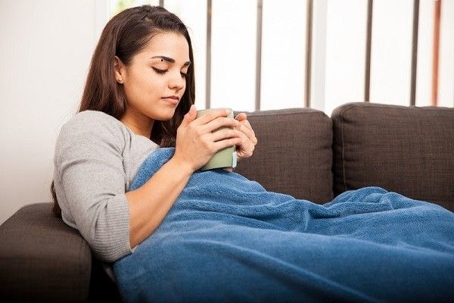 woman with mug snuggled on couch