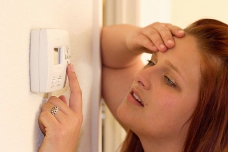 distressed woman adjusting thermostat