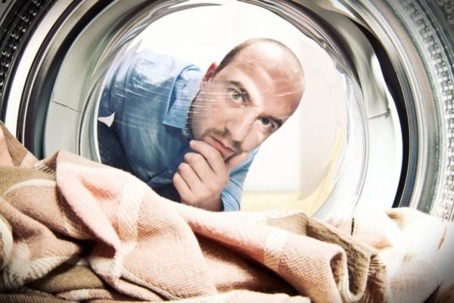 man peering into washing machine